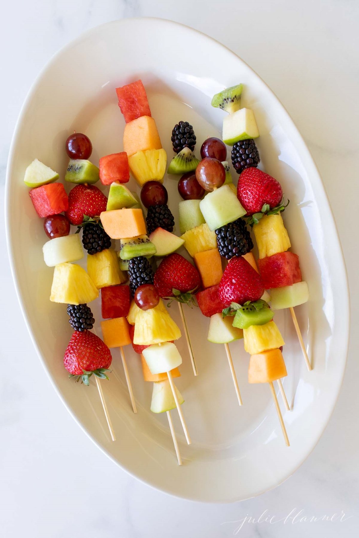 fruit skewers on a white platter