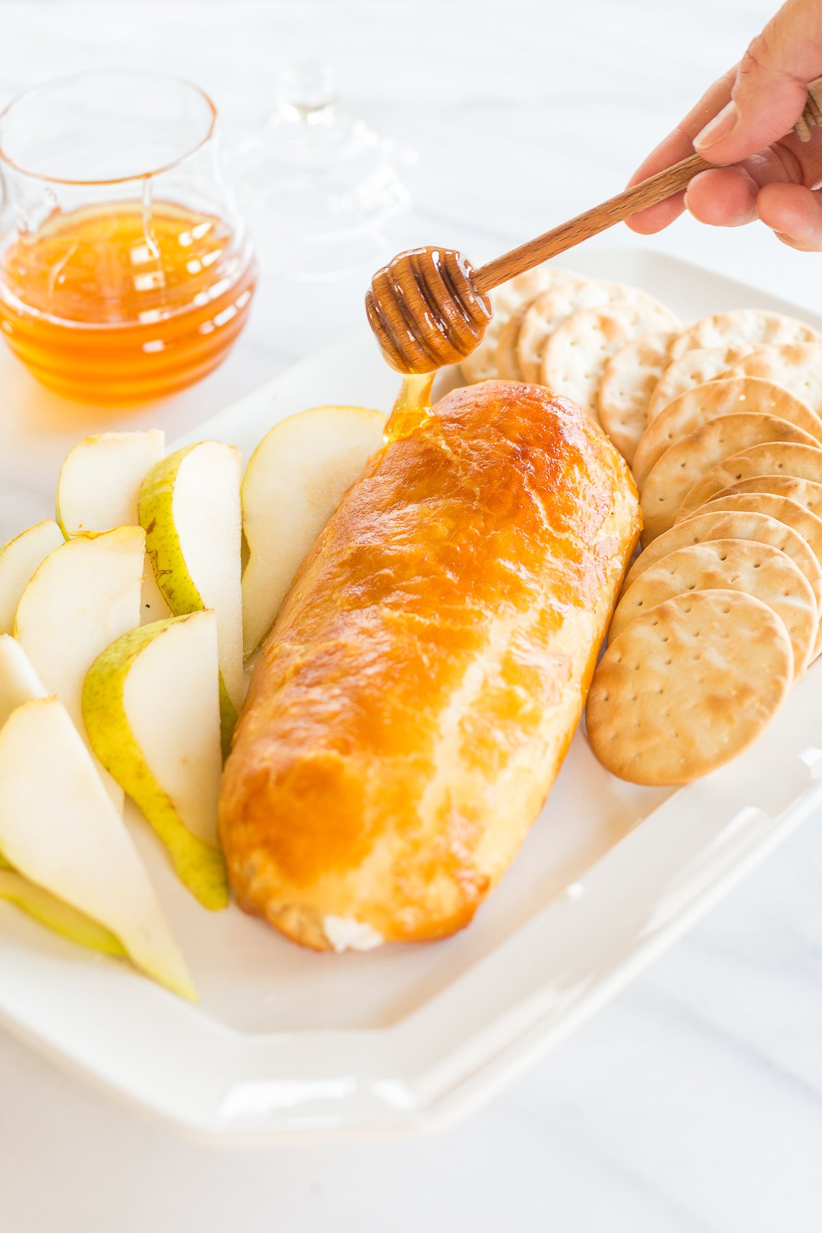 Honey dipper drizzling honey over appetizer tray