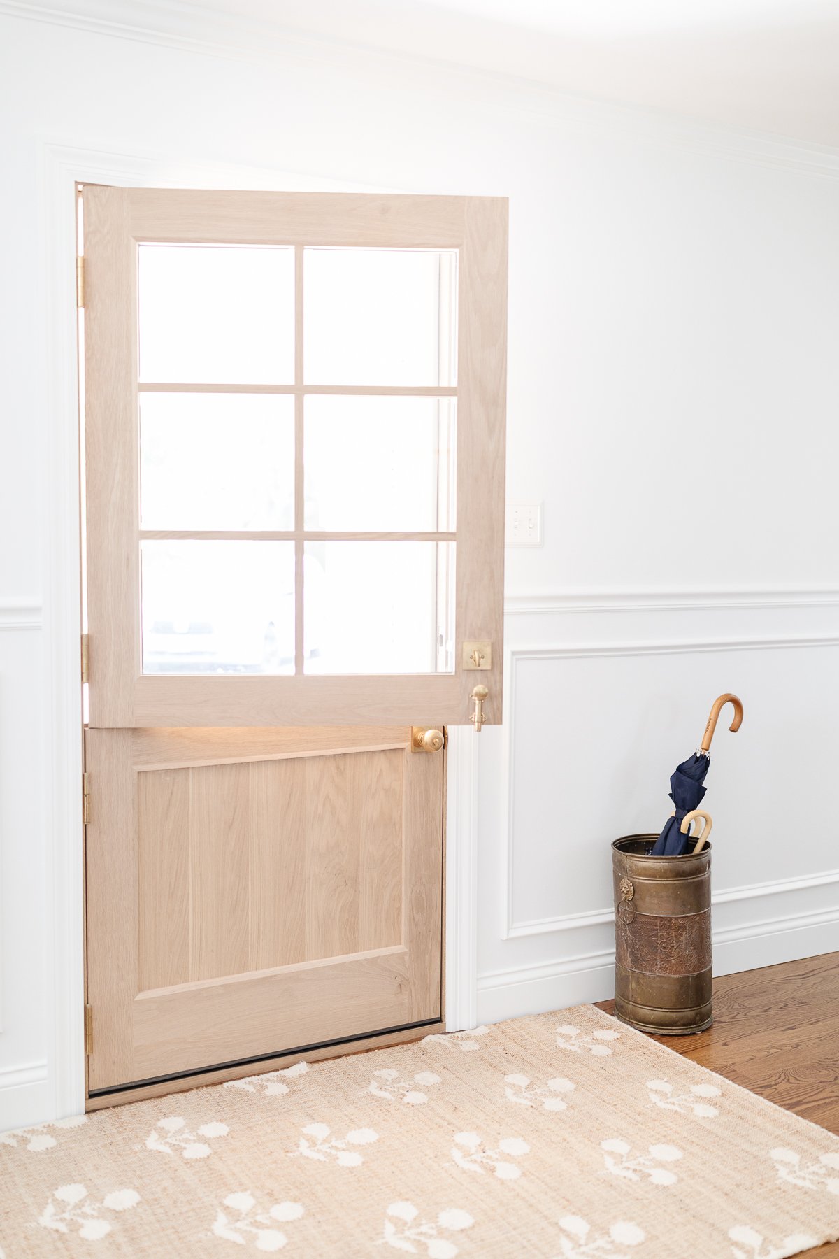 A wooden Dutch door with a neutral rug and Sherwin Williams Extra White walls.