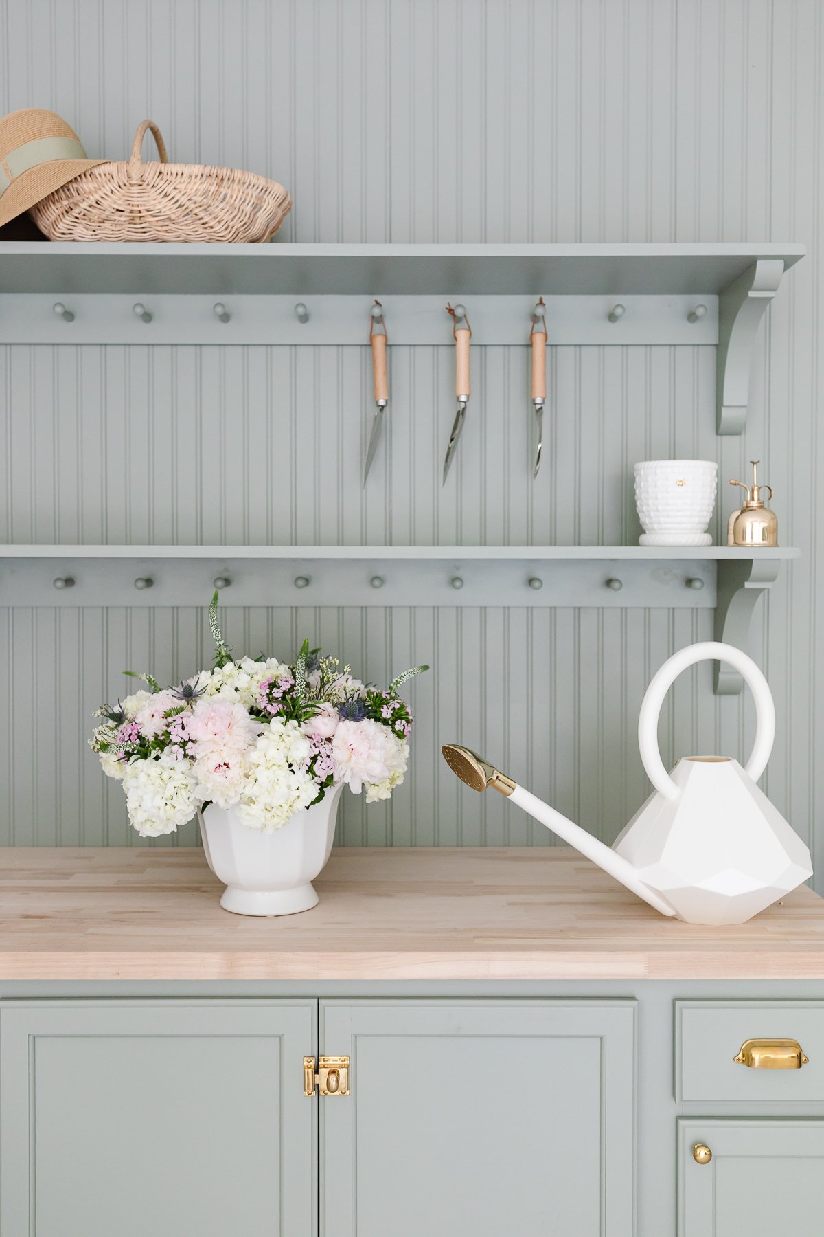 A green potting bench with a white vase full of Trader Joe's flowers