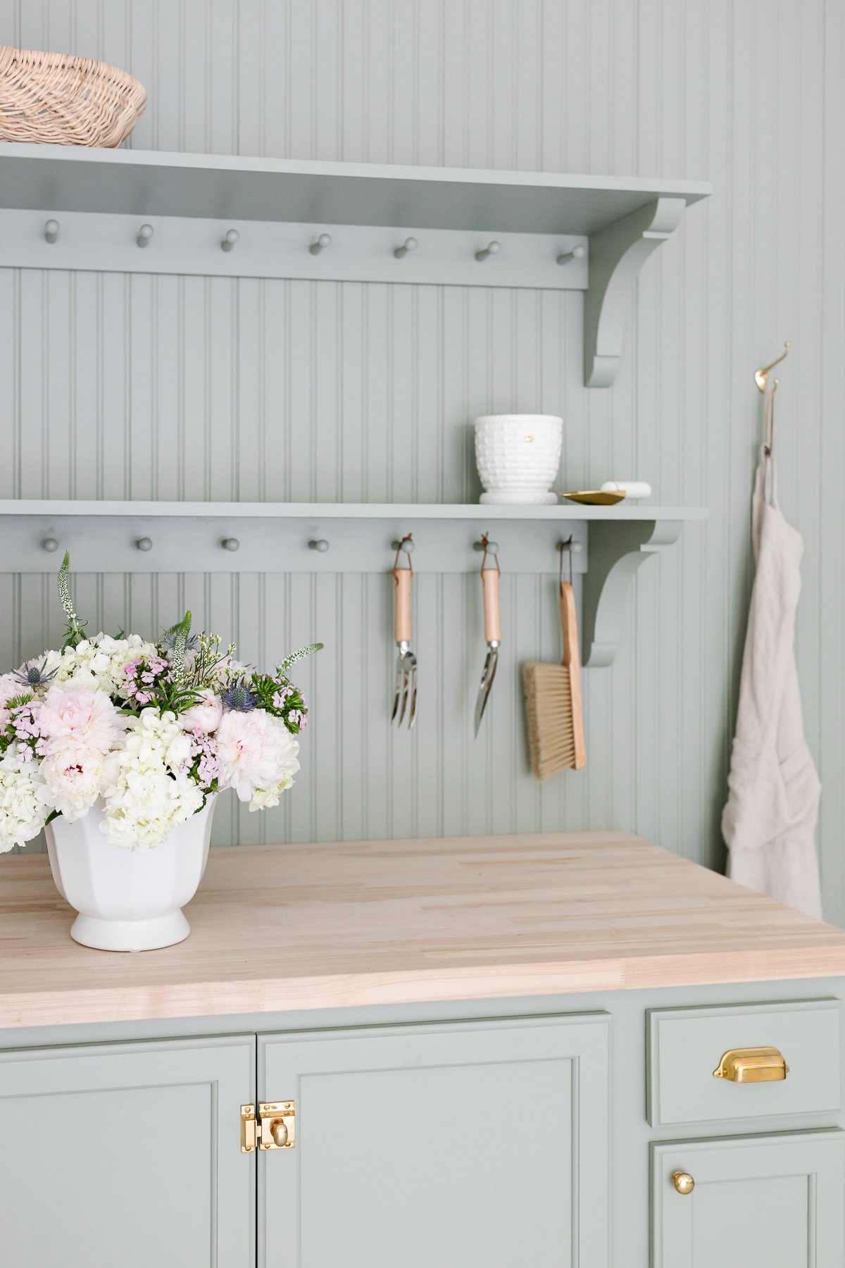 A green potting bench with a white vase full of Trader Joe's flowers 