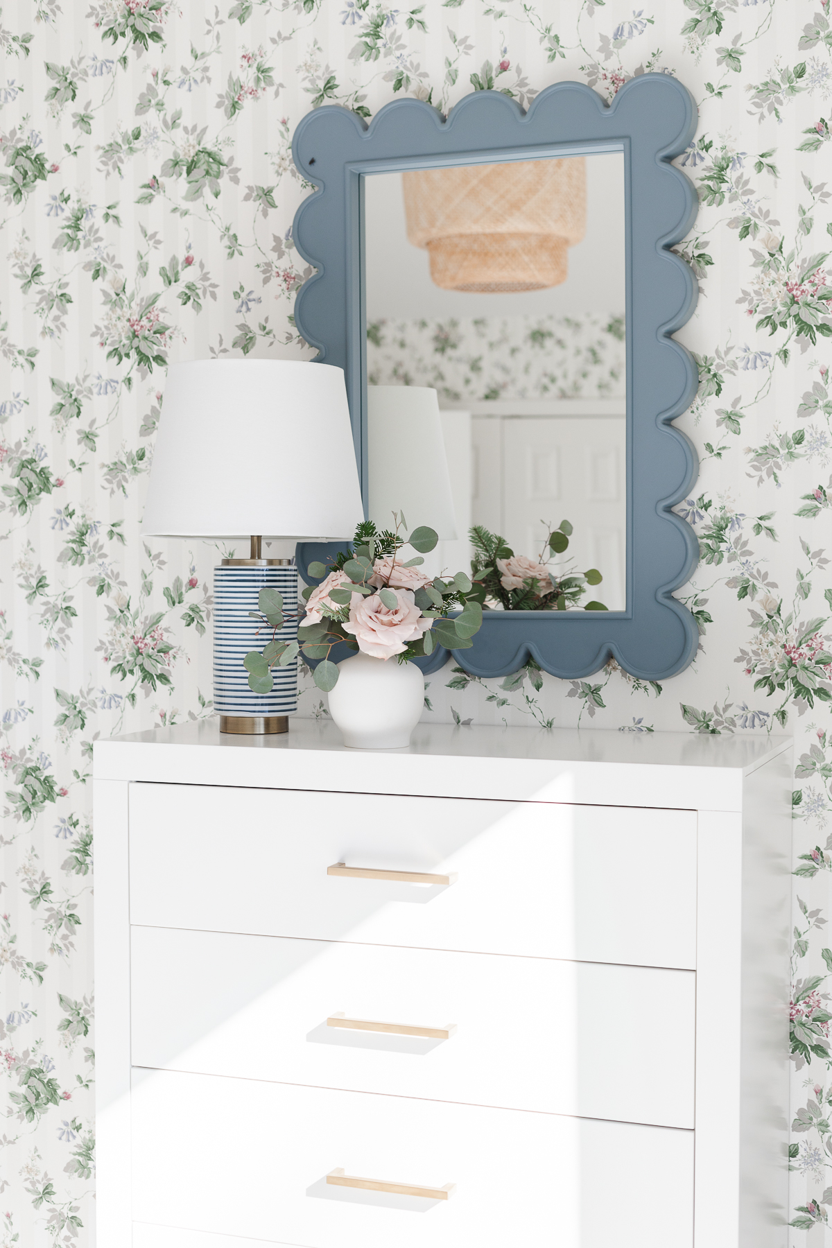 A bedroom with floral pastel wallpaper on the walls