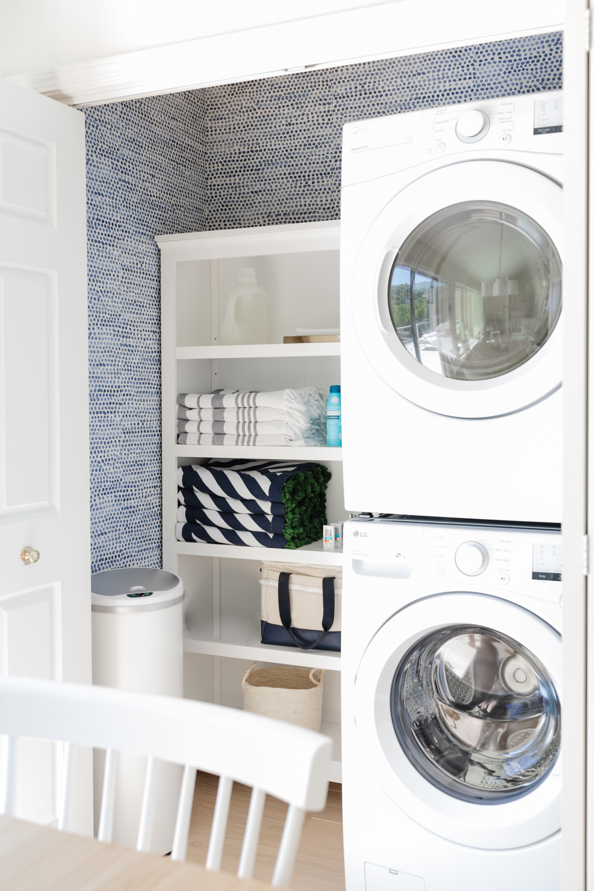 A laundry closet with blue and white Amazon wallpaper on the walls.