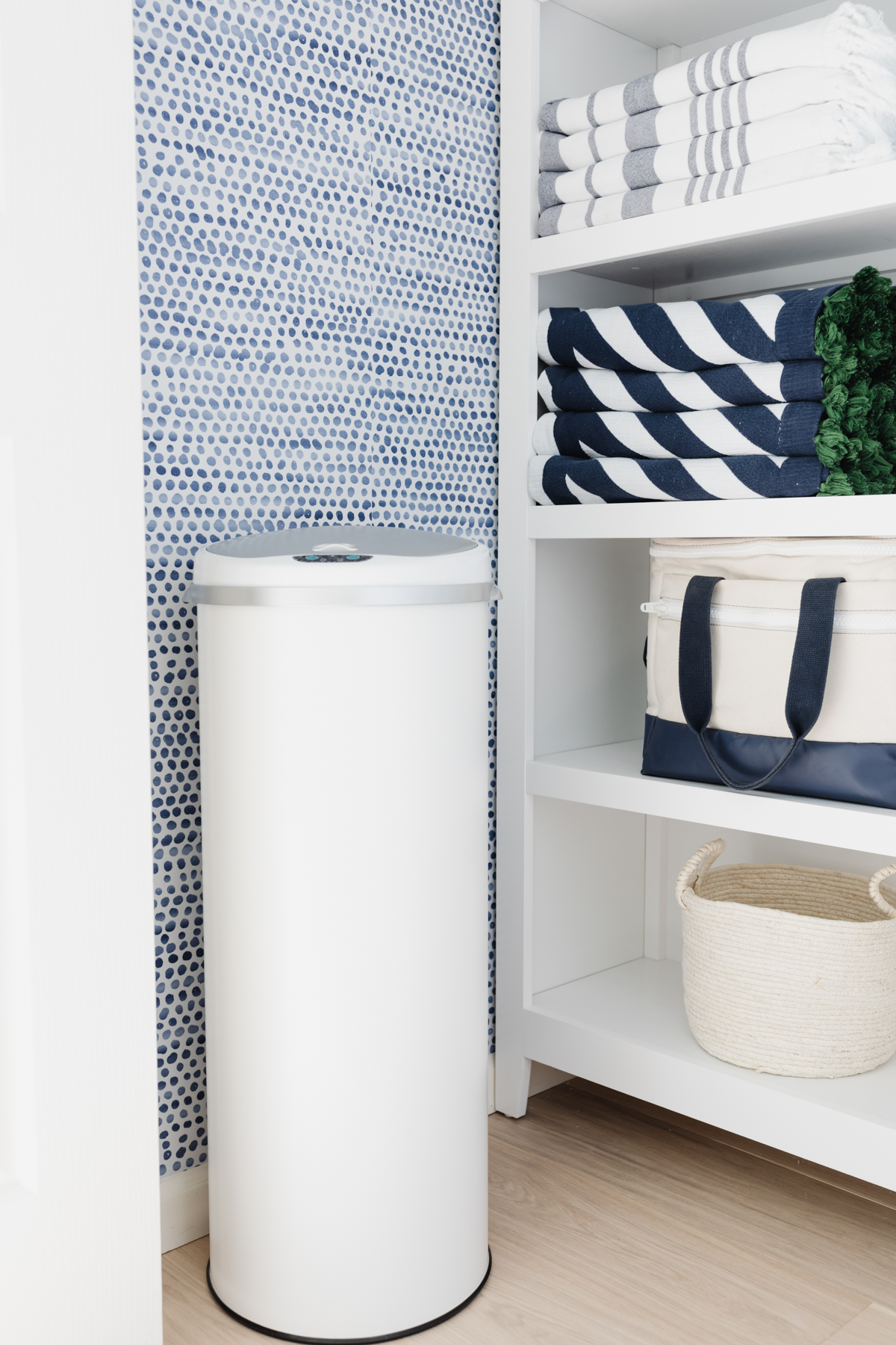 A laundry closet with blue and white Amazon wallpaper on the walls.