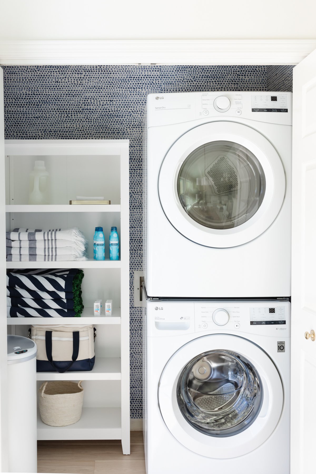 A laundry closet with blue and white Amazon wallpaper on the walls.