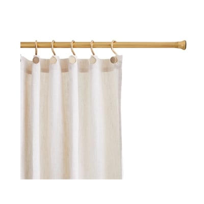 A brass shower curtain rod with a beige curtain hanging from it.