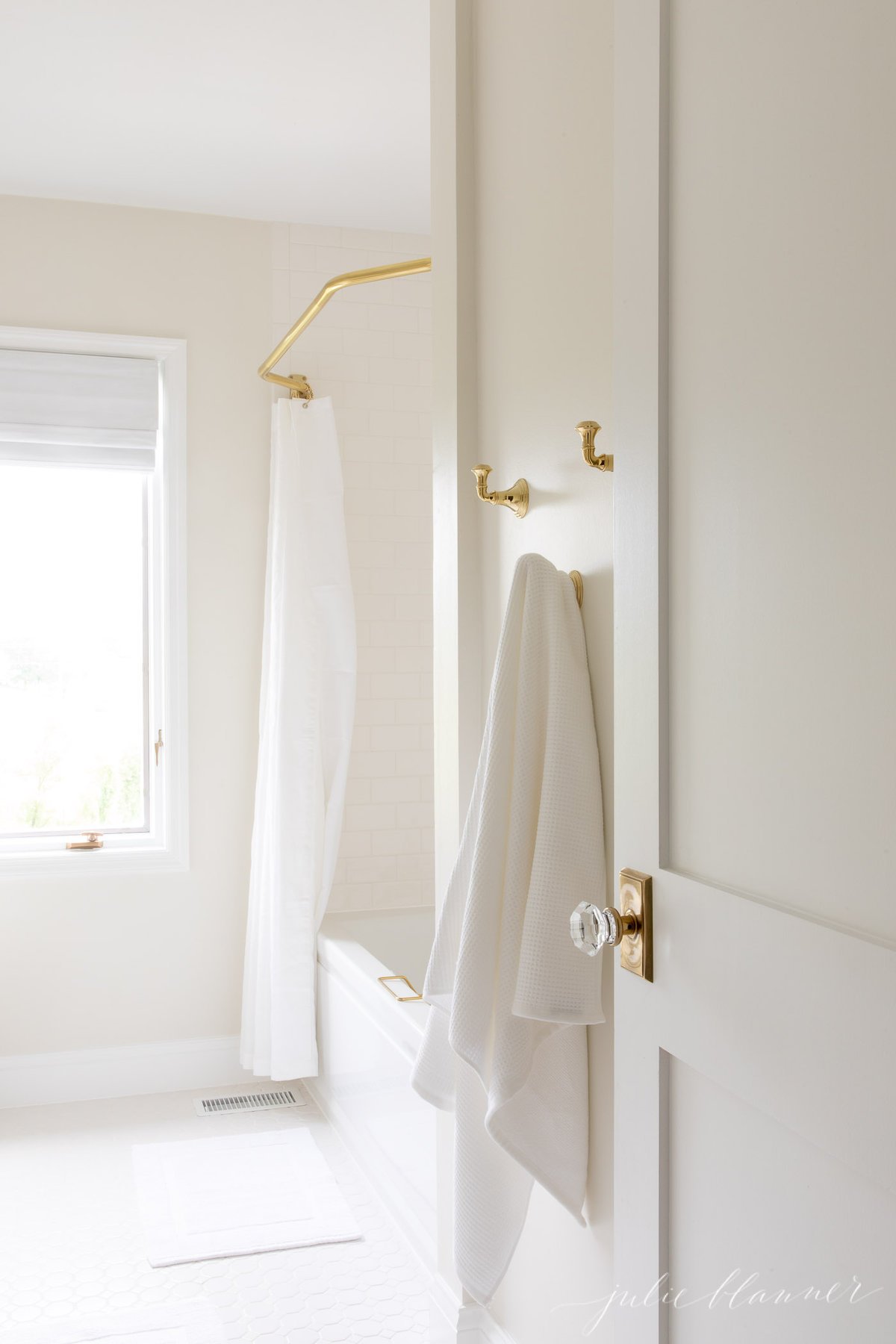 A white shower with a brass shower curtain rod.