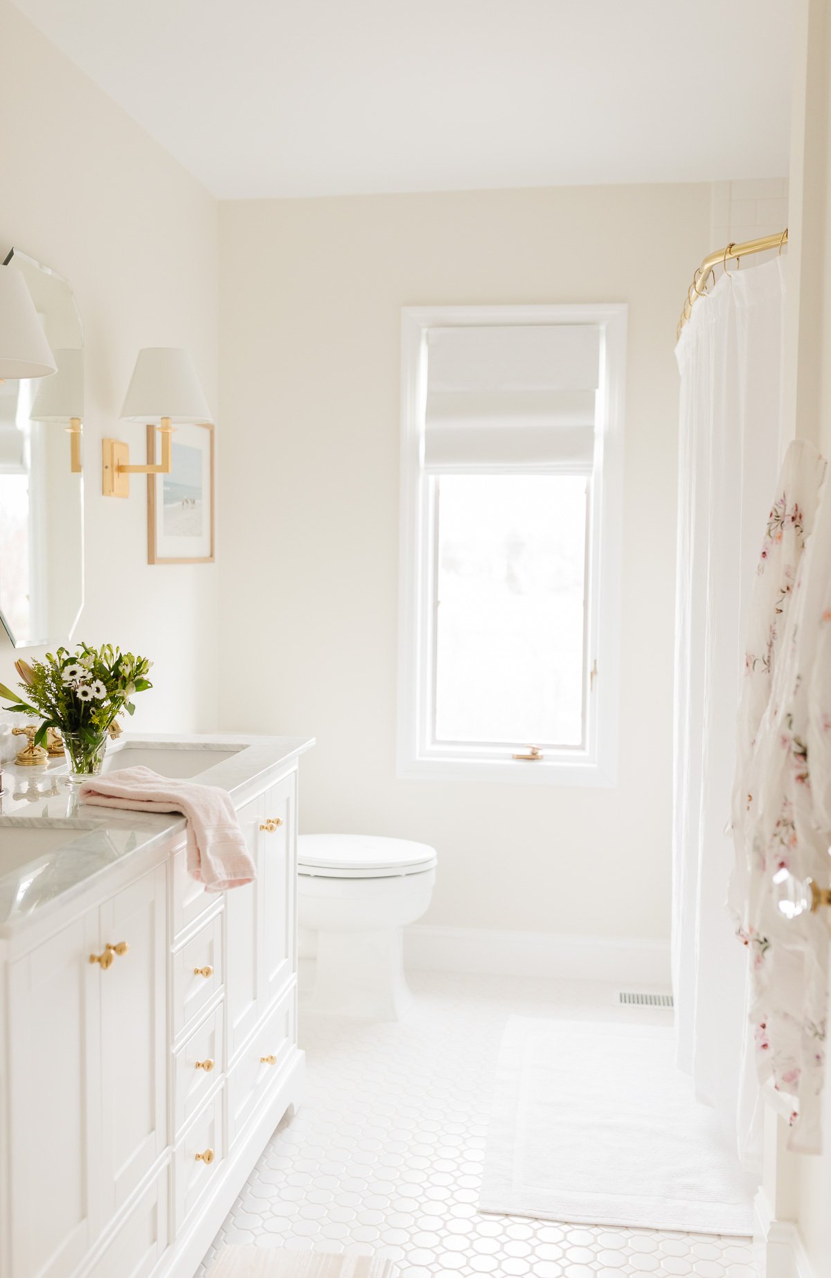 A white shower with a brass shower curtain rod.