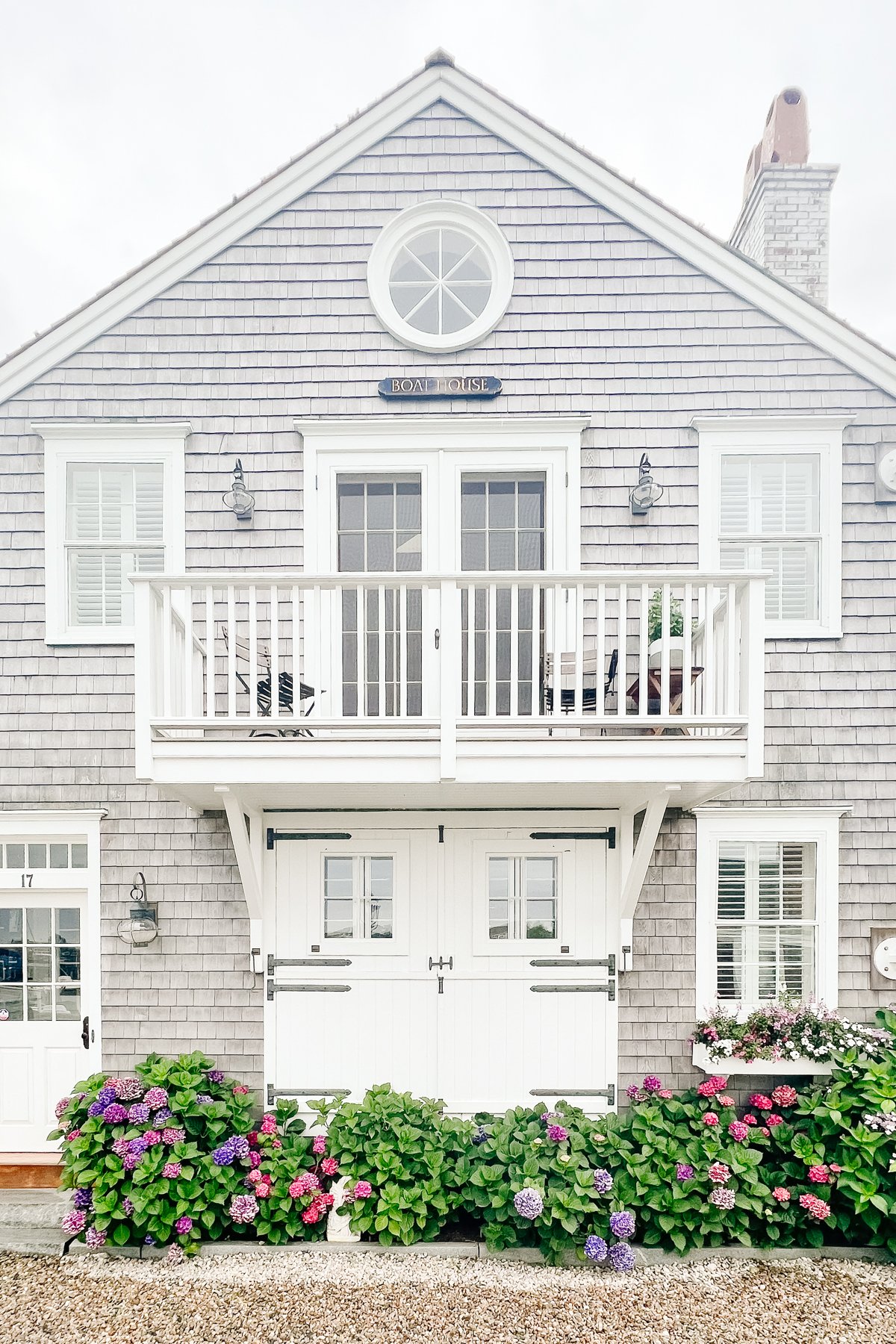 A gray shingled Nantucket house with a white carriage garage door.