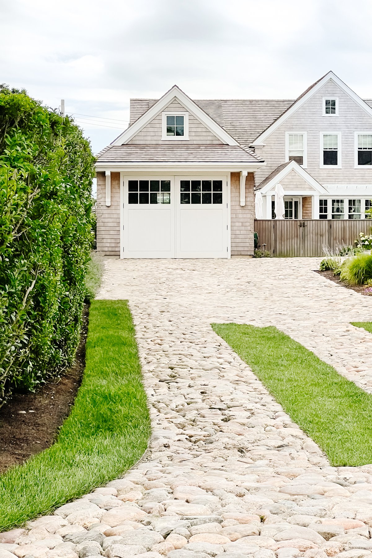 A gray shingled Nantucket house with a white carriage garage door.