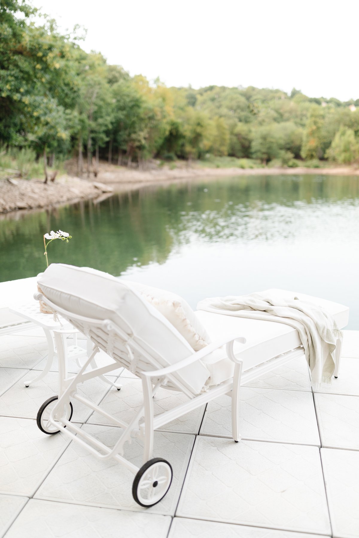 white chaise lounge chair draped with a towel on a dock