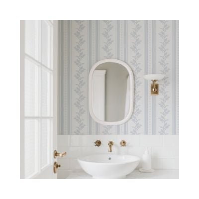 A bathroom with a round mirror, white sink, gold faucet, soap dispenser, and stylish Amazon Wallpaper, next to a door with glass panes.
