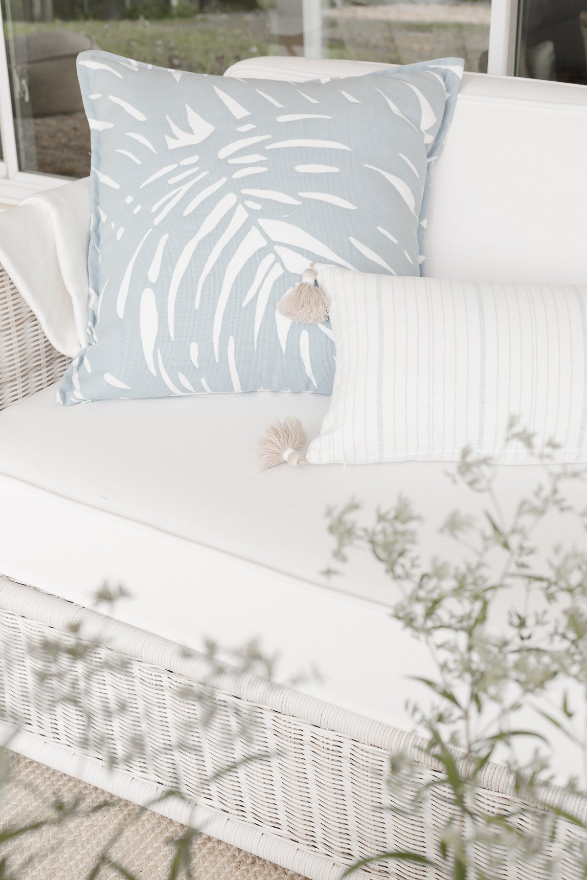 An outdoor patio decorated with white furniture and blue and white outdoor fabric pillows