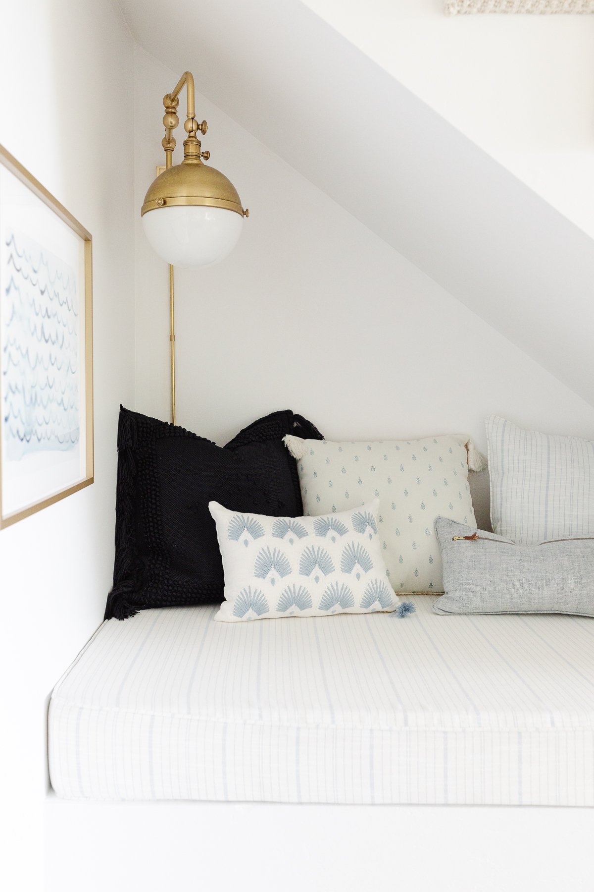 A reading nook under a staircase, upholstered with blue and white striped outdoor fabric