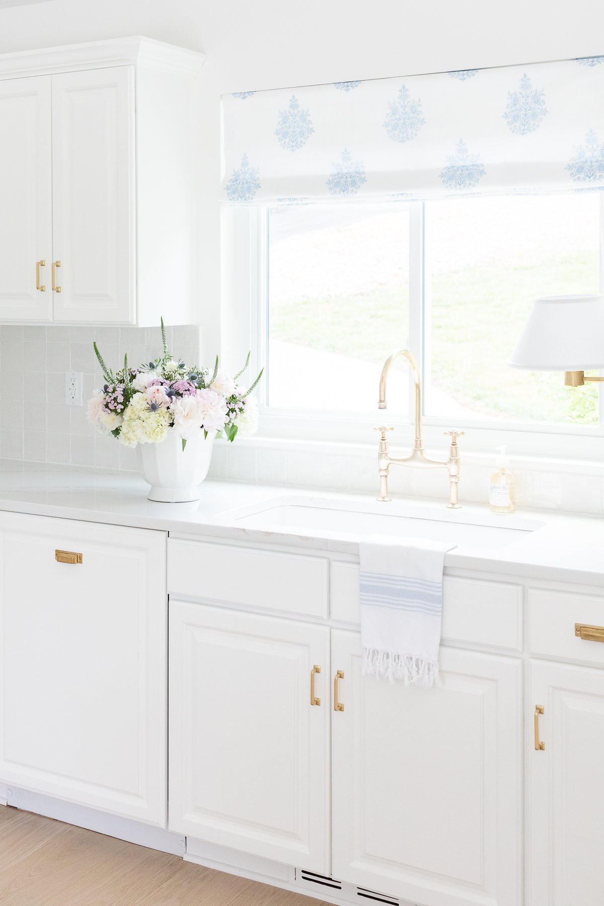 A white kitchen with a shiny stacked square tile backsplash. 
