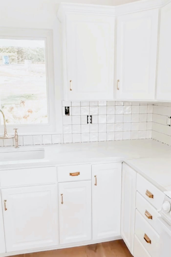 Square stacked backsplash being installed in a white kitchen.