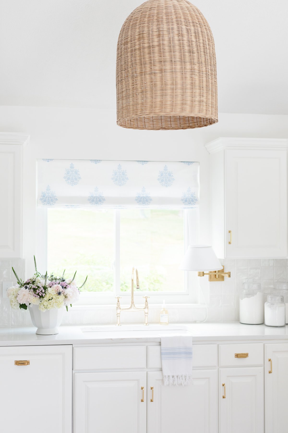 A glossy stacked tile backsplash in a white kitchen, glass canisters with baking supplies rest on the counter.