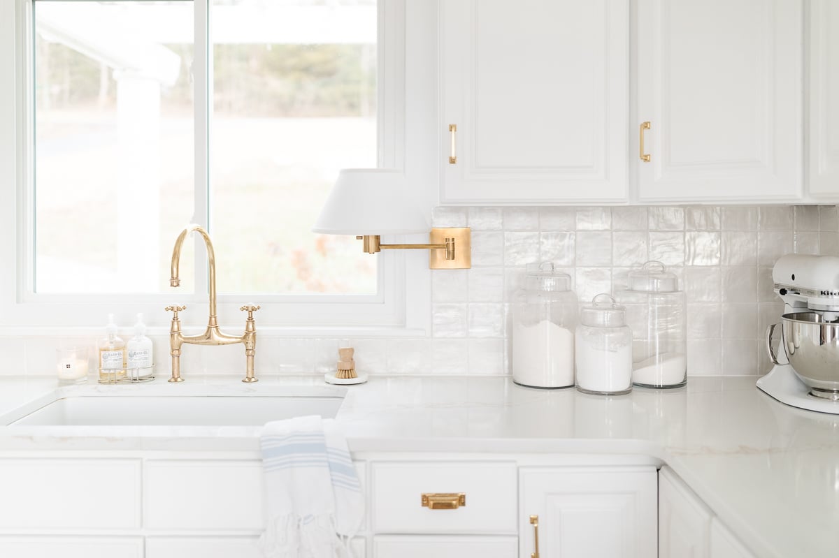 A white kitchen with a shiny stacked square tile backsplash.