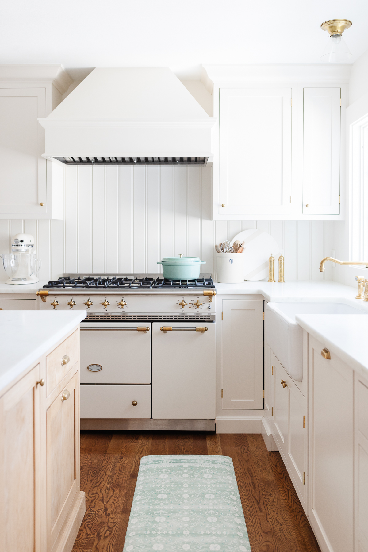 A kitchen with white cabinets and a green rug.