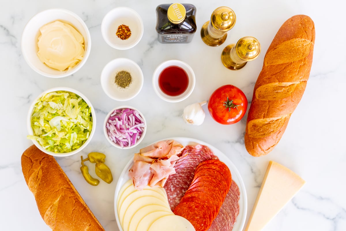 Ingredients for a tiktok grinder sandwich laid out on a marble countertop.
