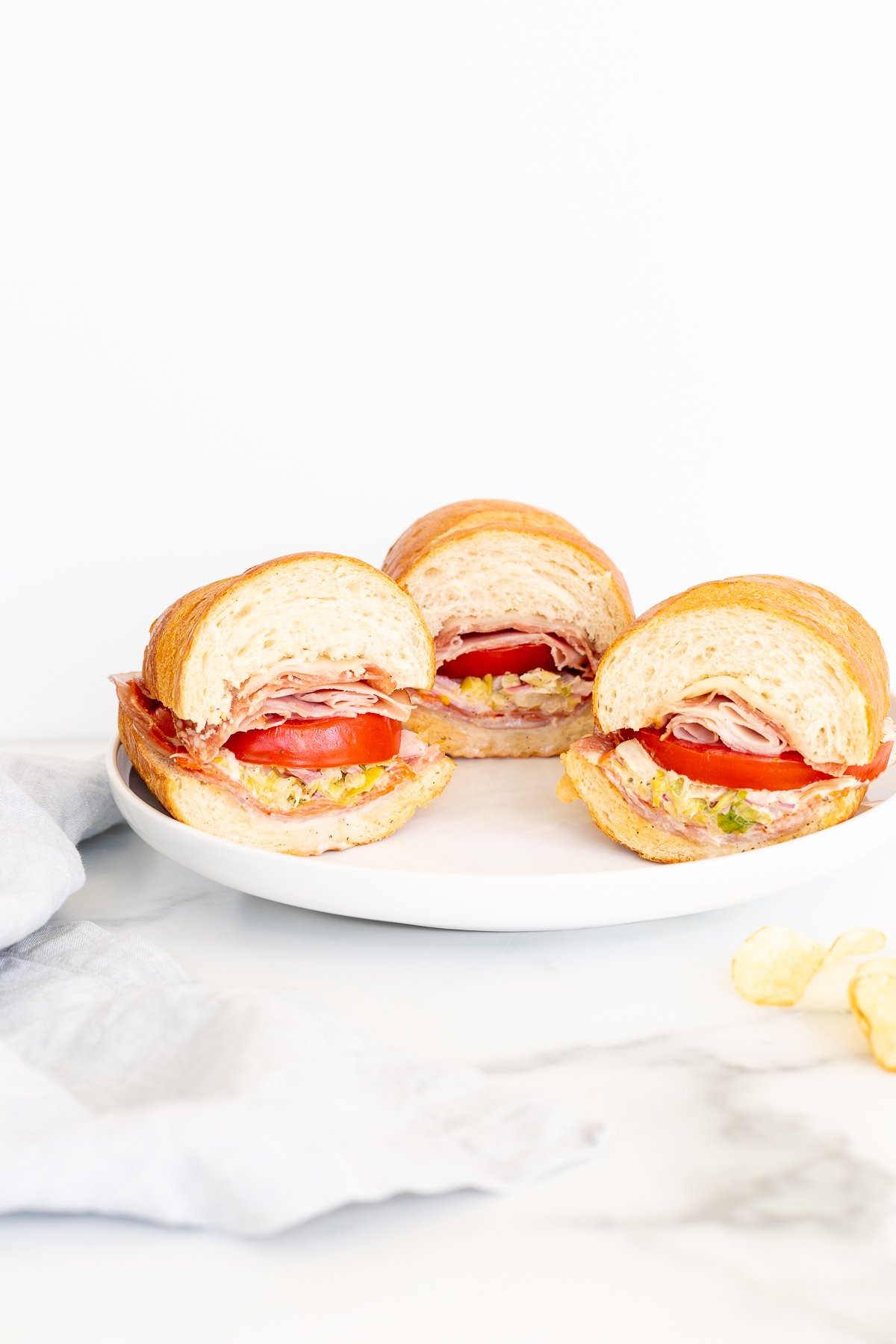 Three grinder sandwiches on a white plate.