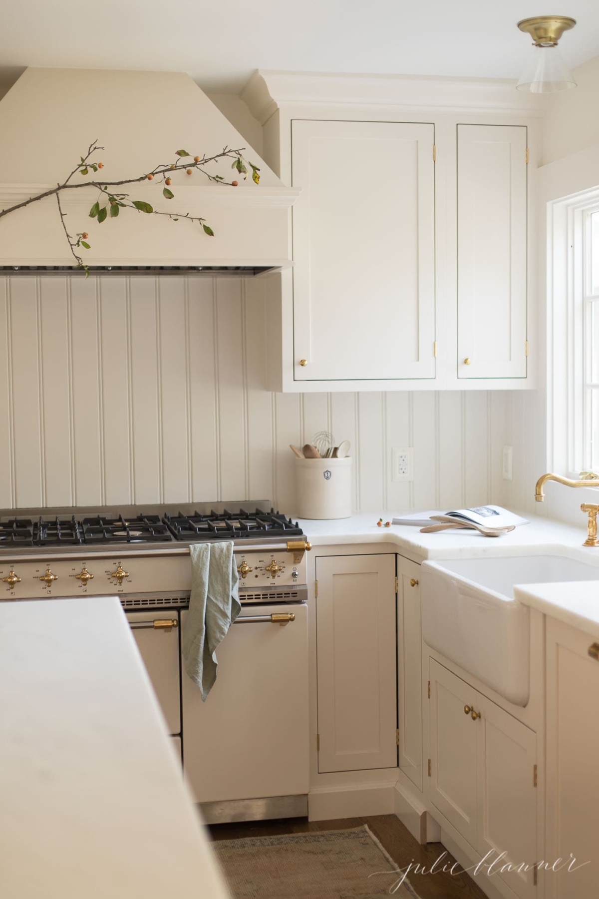 A white kitchen with fall branches hanging over the range.