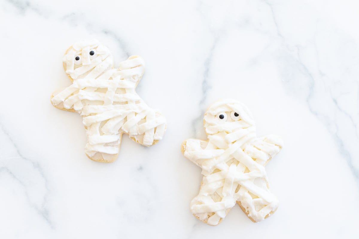 Mummy Halloween sugar cookies laid out on a white surface.