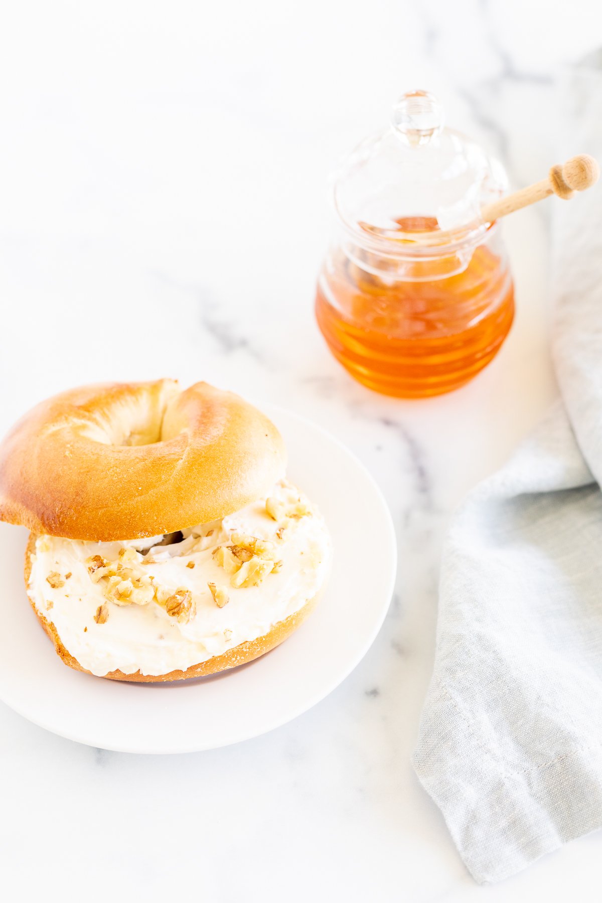 A Honey Walnut cream cheese bagel on a white plate.