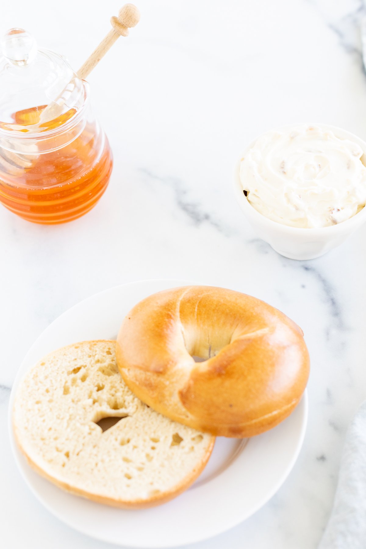 A bagel with honey walnut cream cheese on a white plate.
