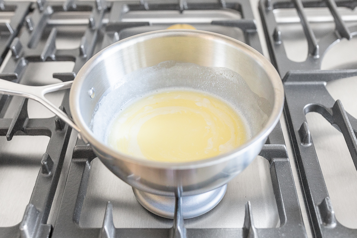 A pan filled with butter and sugar on a stove top.