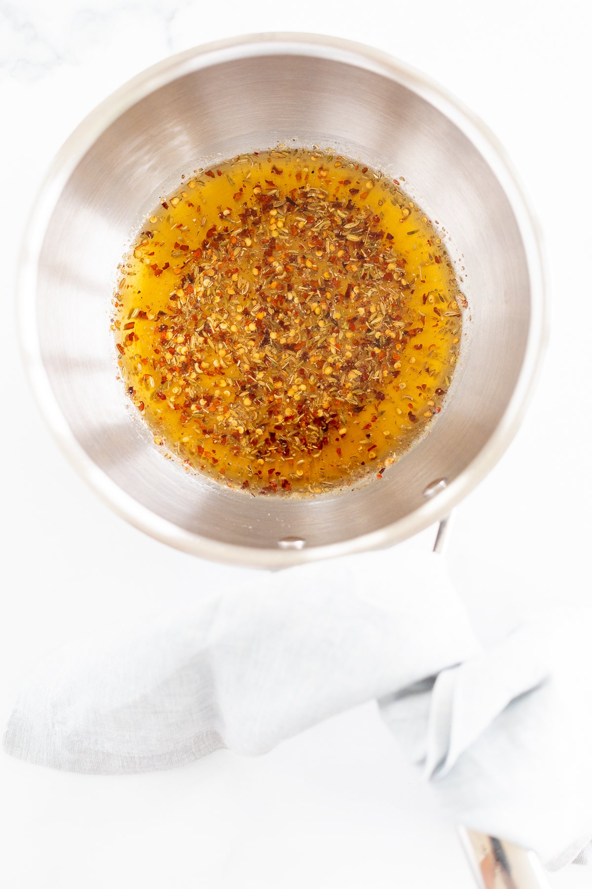 A pan filled with spices and honey on a white surface.