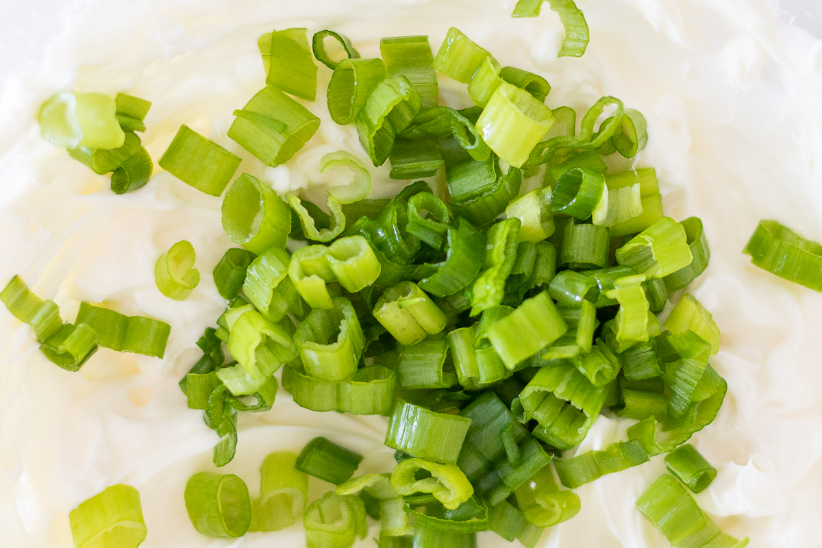 A bowl of cream cheese with green onions (scallion) on top.