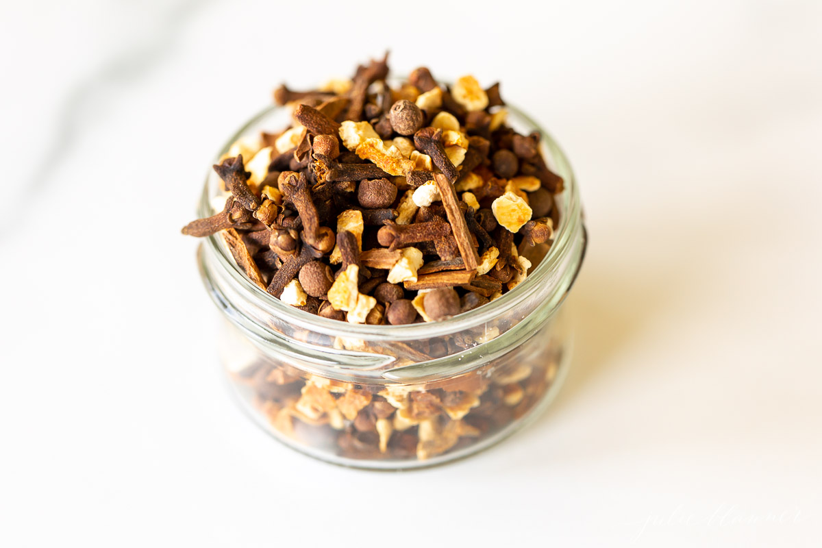 A glass jar filled with cinnamon and other spices, infused with the aroma of mulling spices.