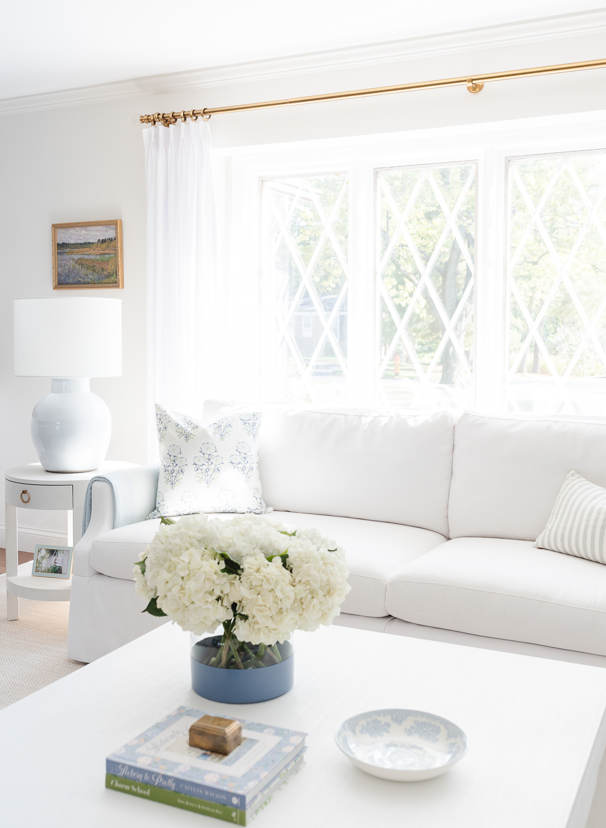 A white couch with pinch pleat drapes in a living room.