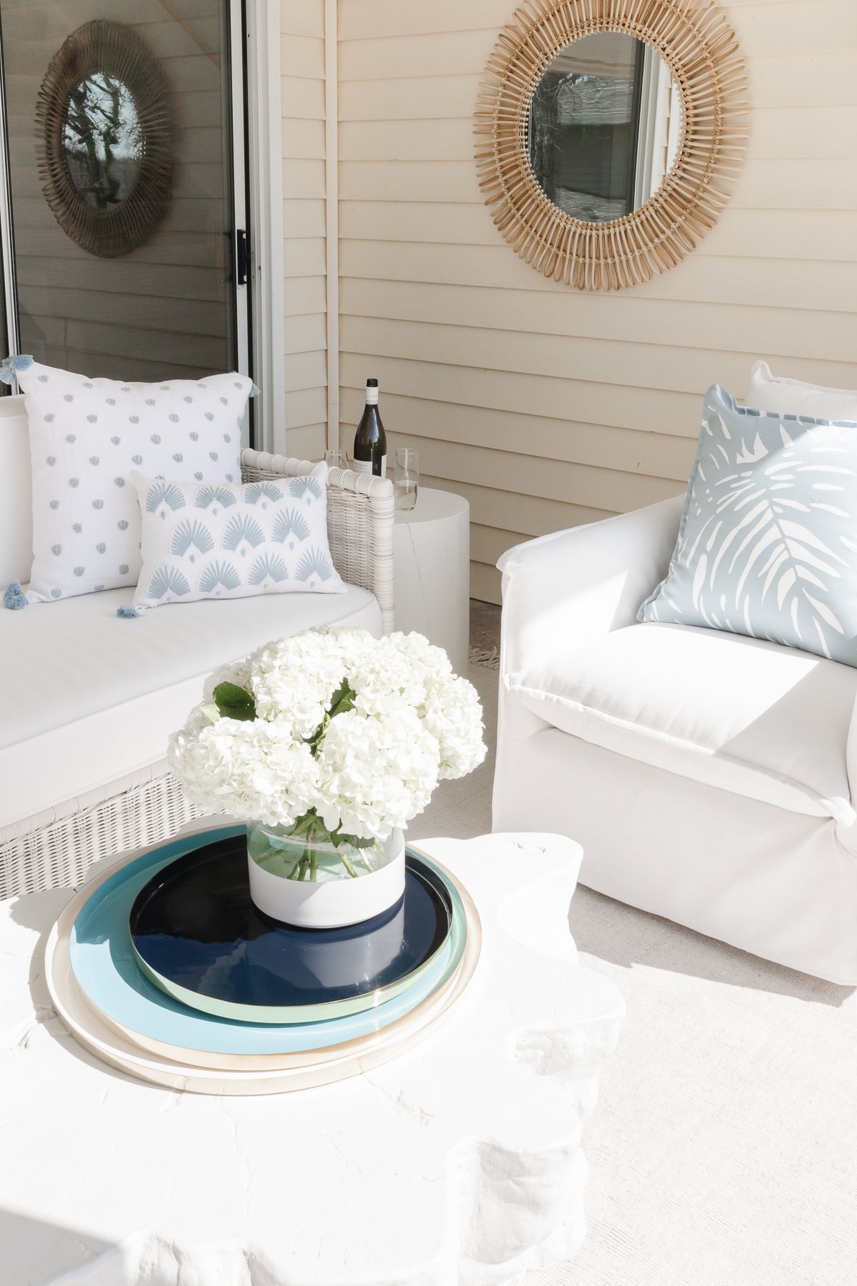 A white and blue patio with a table and chairs and a vase of white hydrangea