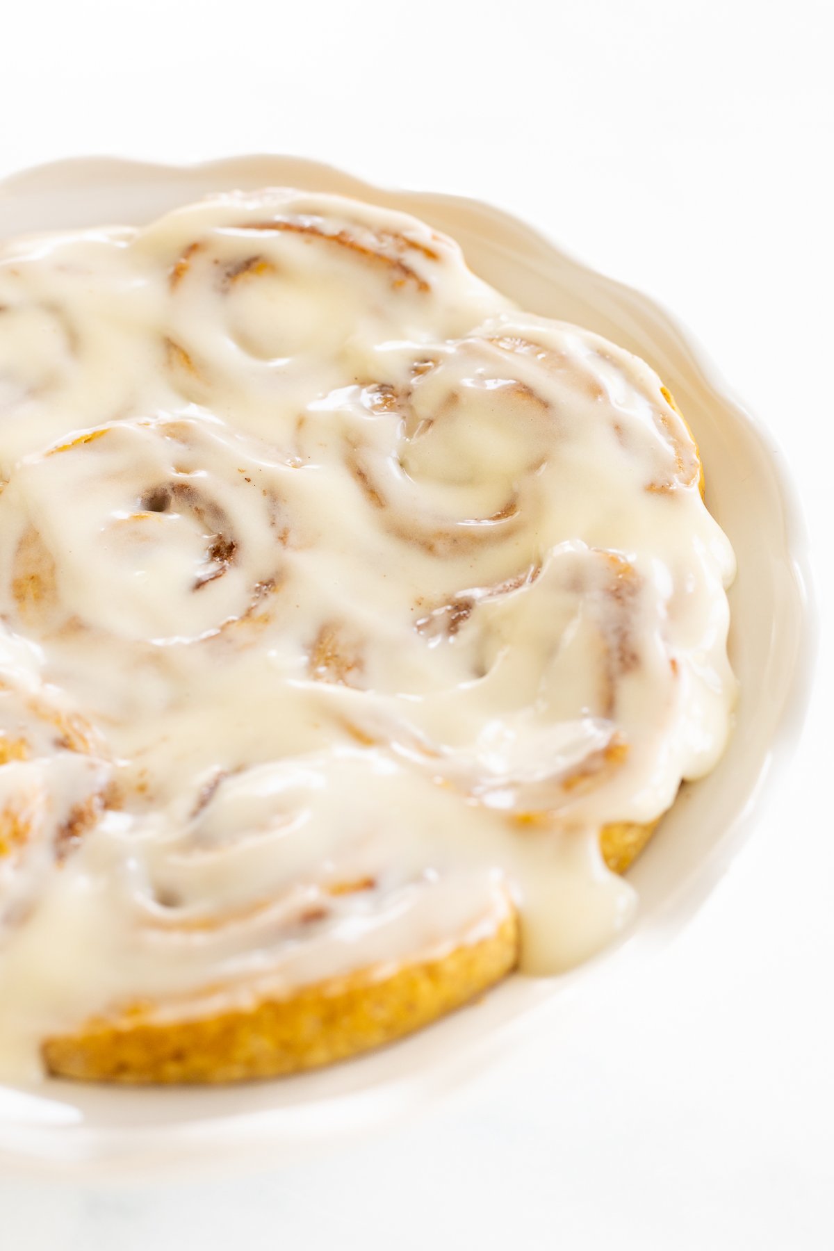 A plate of pumpkin cinnamon rolls with icing on it.