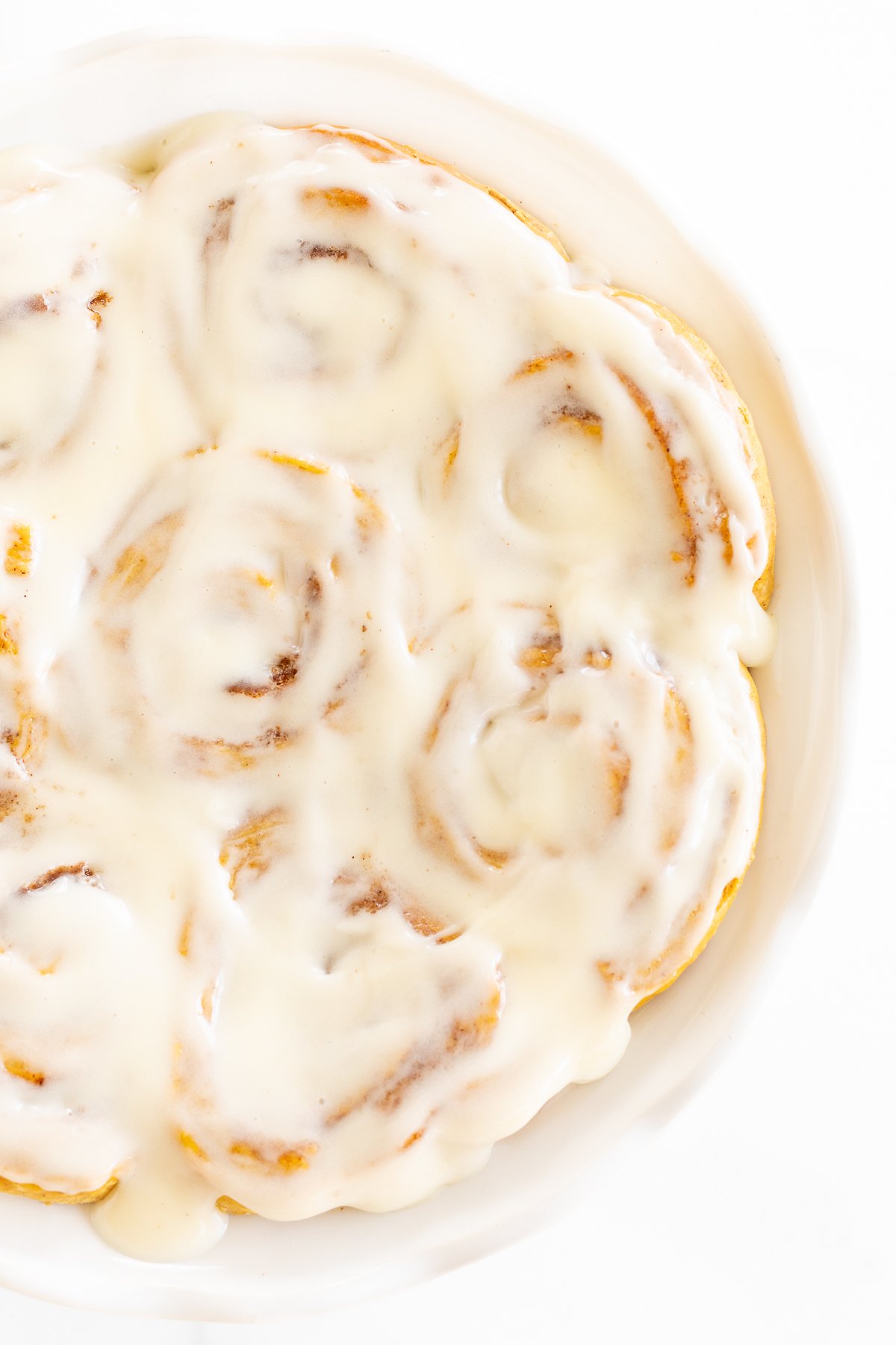 A plate of pumpkin cinnamon rolls with icing on top.