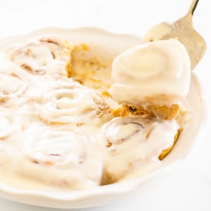 A fork is being used to take a bite of a cinnamon roll, specifically pumpkin cinnamon rolls.