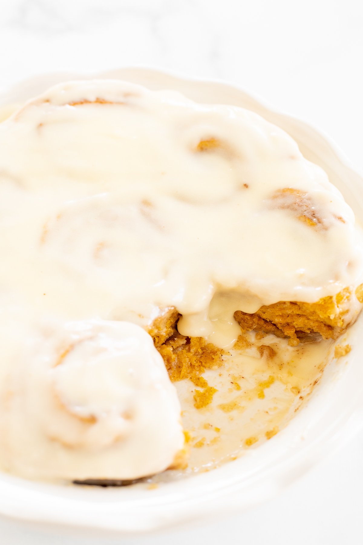 A plate of Pumpkin Cinnamon Rolls with cream cheese frosting.