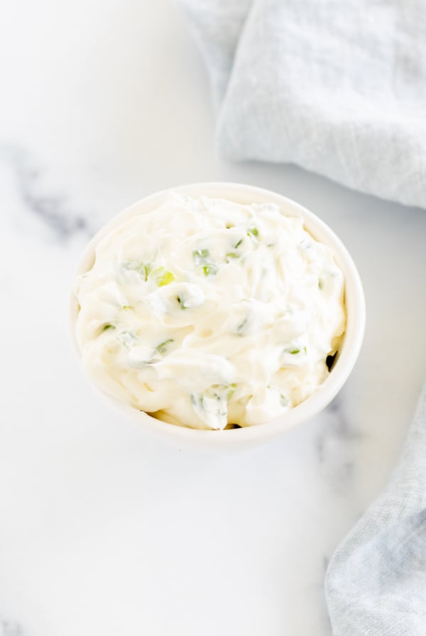 A white bowl with whipped scallion cream cheese.