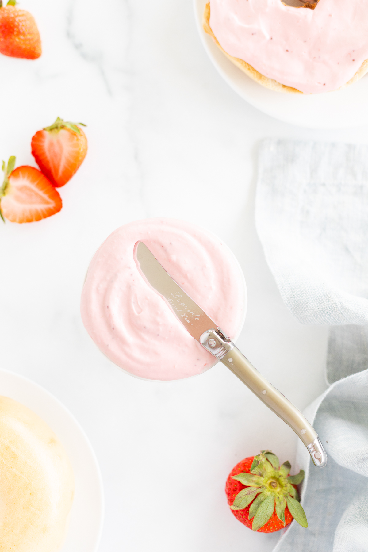A knife on top of a bowl of strawberry cream cheese.