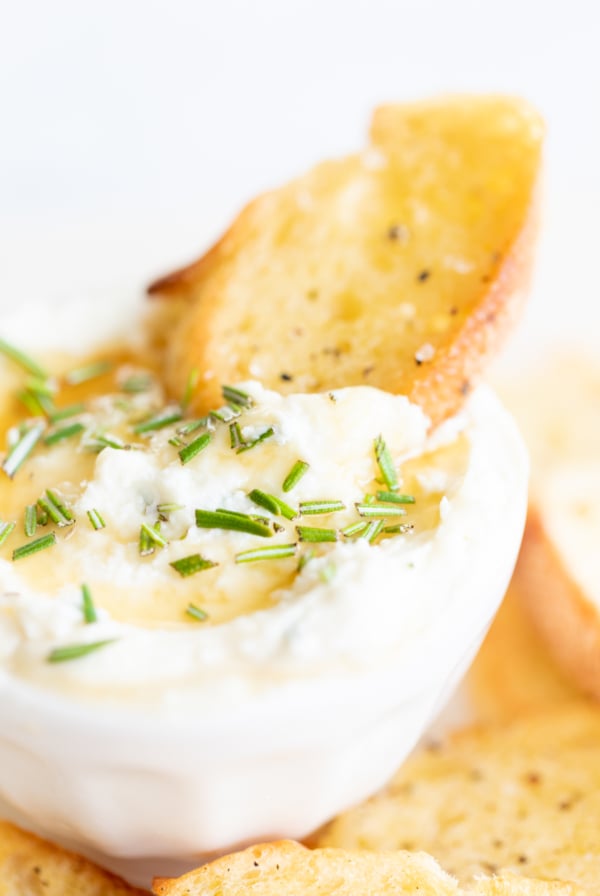 A bowl of dip with croutons and a sprig of rosemary, perfect for easy Thanksgiving appetizers.