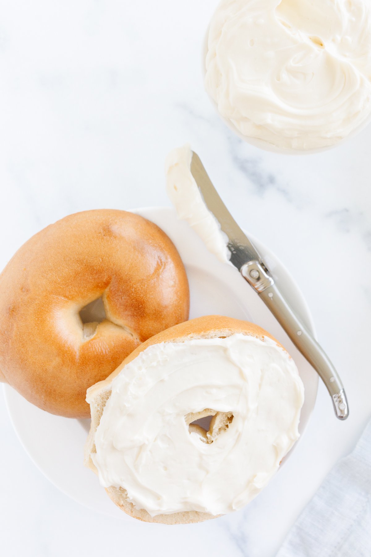 A bagel with whipped cream cheese on a plate.