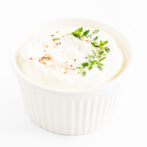 A white bowl of whipped ricotta with a sprig of thyme.