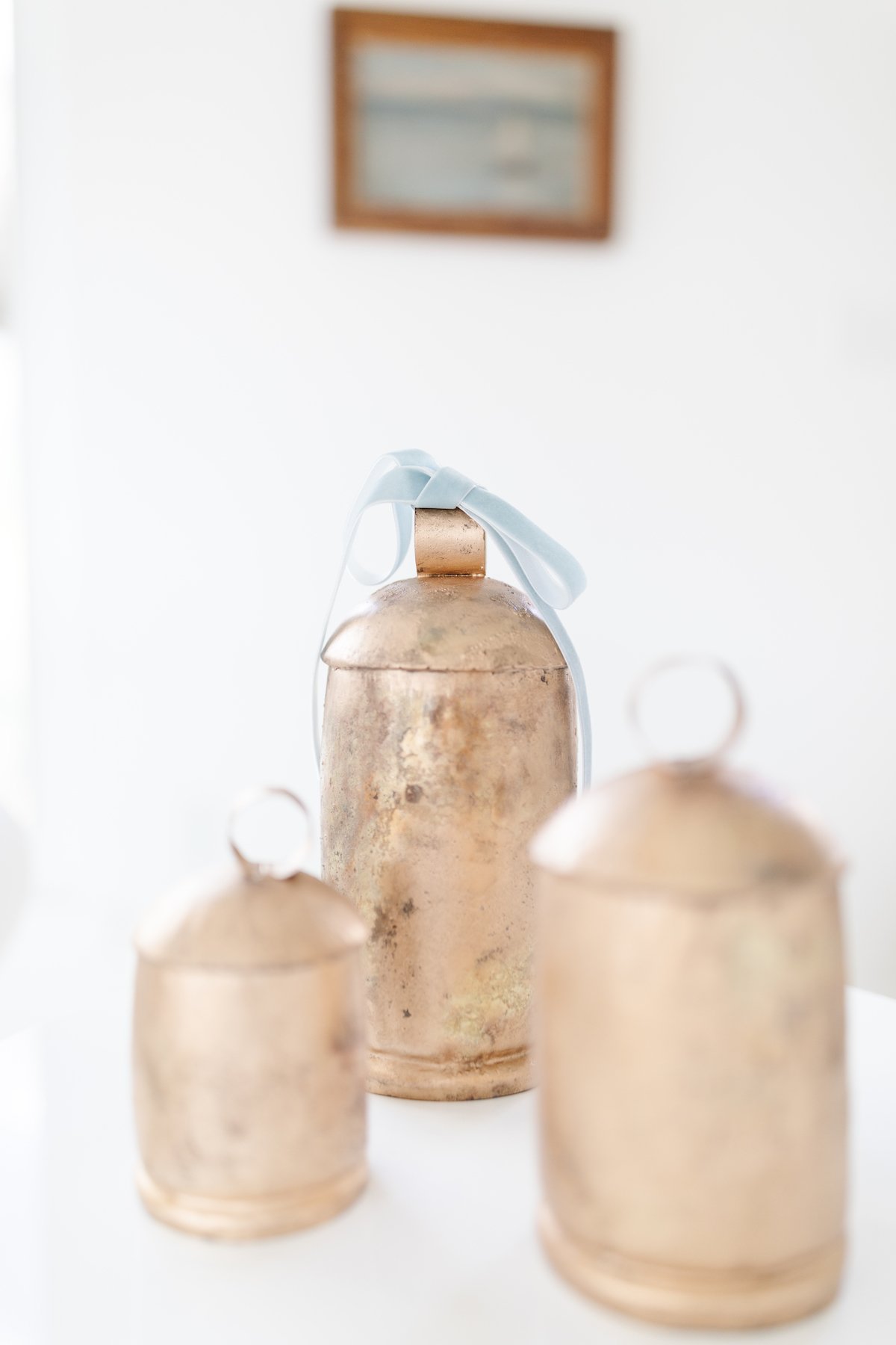 Three brass bells on a white table.