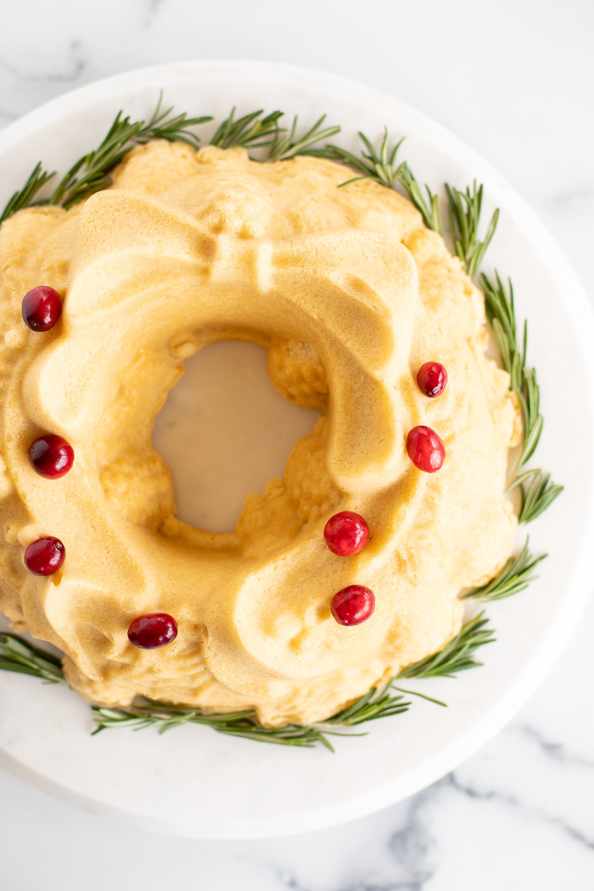 A white plate with a cranberry wreath on it, showcasing a delightful Christmas Bundt Cake.