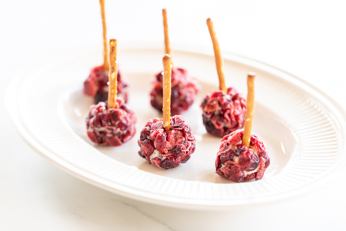 Cranberry Christmas cheese ball pops on a white plate.