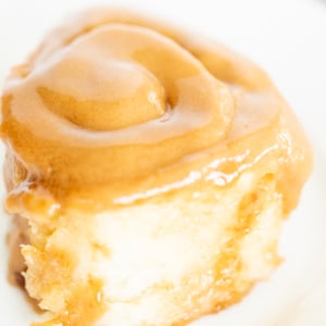 A Cookie Butter Cinnamon Roll on a plate, accompanied by a fork.