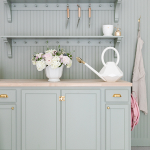 A green kitchen with shelves and a watering can.