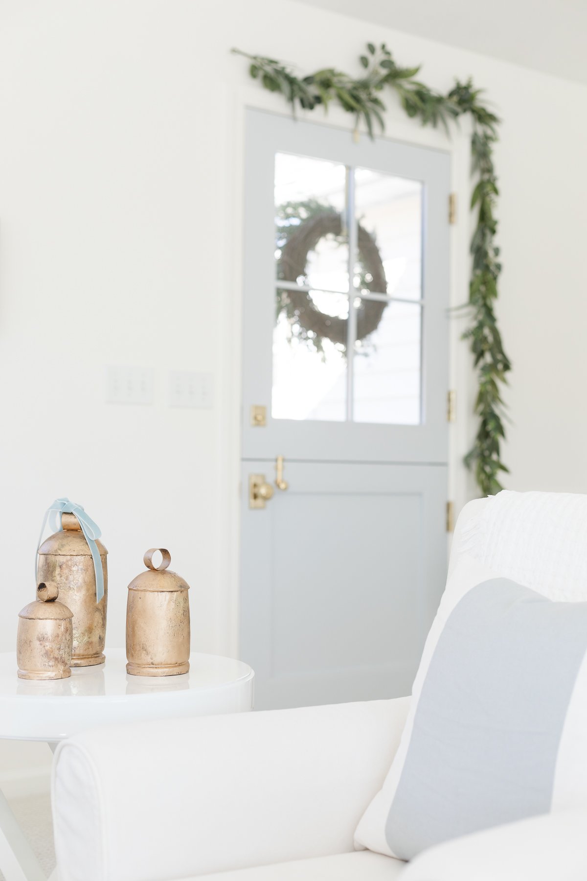 A white living room with a wreath on the door.